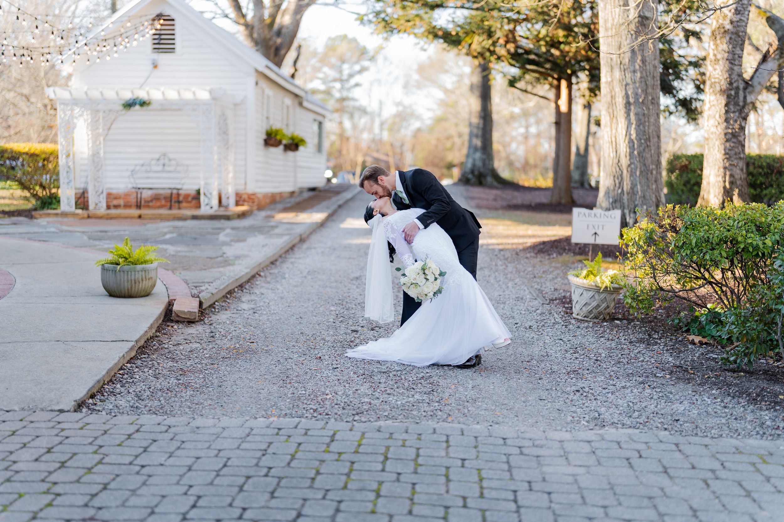 Multiple frames capture the movement of a bride's long white dress train being styled on a brick pathway.