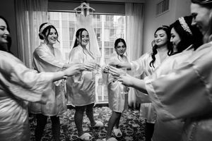 Black and white photo of wedding party dancing and celebrating together indoors.