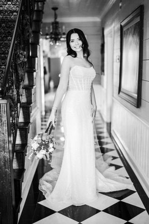 Black and white photos of a bride in a white dress on a checkered floor hallway.