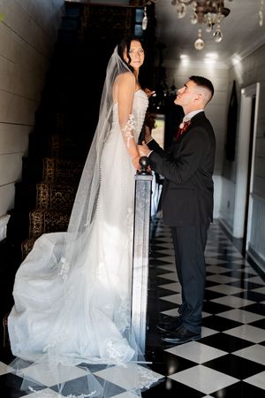 A couple shares a romantic dance moment on a black and white checkered floor at their wedding celebration.