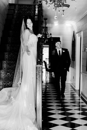 Elegant wedding scene in a hallway with checkered floors and chandelier lighting.