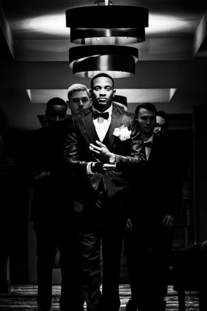 Black and white photo series showing people in formal suits and sunglasses posing in dramatic noir style lighting.