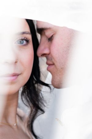 Romantic close-up portrait of a couple about to kiss in soft dreamy lighting with white background.