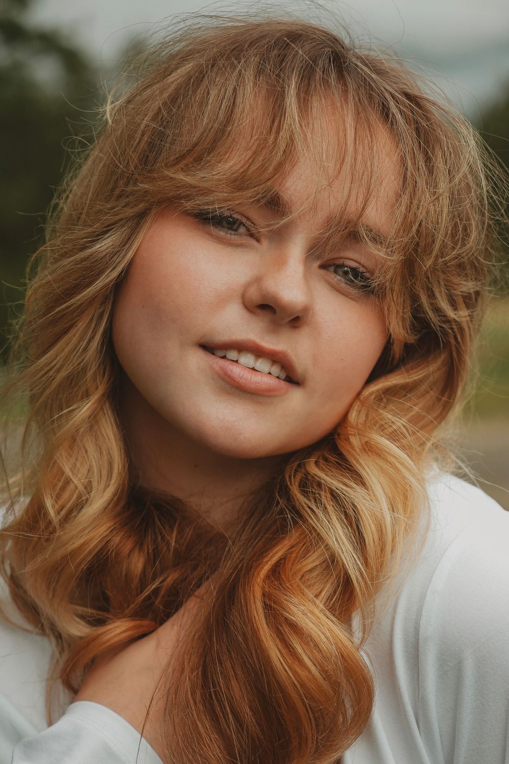 Warm close-up portrait with wavy blonde hair and natural makeup.