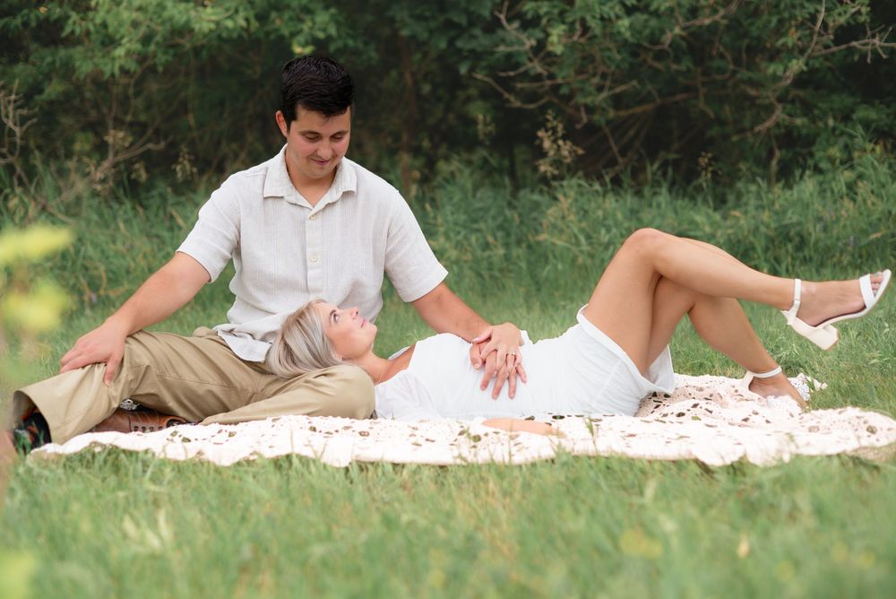 Cheerful figures relaxing on a white picnic blanket in a sunny green meadow on a summer day.