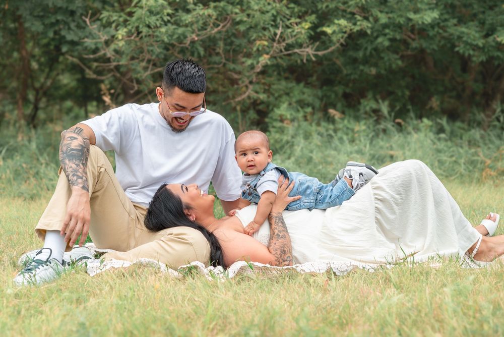 Family enjoying a picnic together in a grassy field on a sunny day.