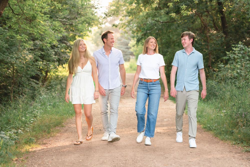 Group of people walking together on a dirt path through lush green scenery on a sunny summer day.
