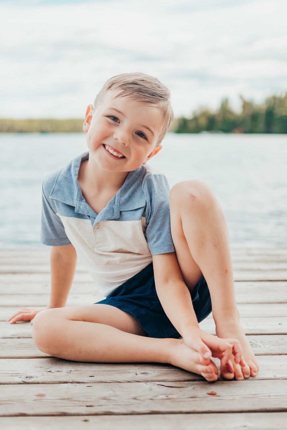 Candid photo series of playful child laying on wooden dock by lake in summer.