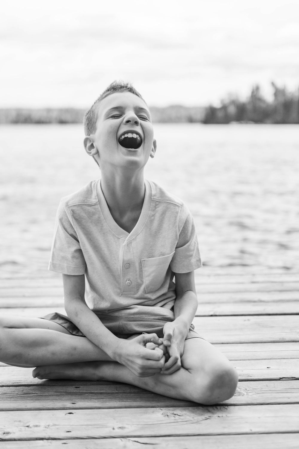 Black and white series of child laughing while relaxing on dock.