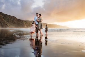 Family enjoying sunset together on reflective beach.