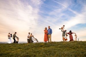 Silhouettes of people dancing and playing on hilltop during sunset.