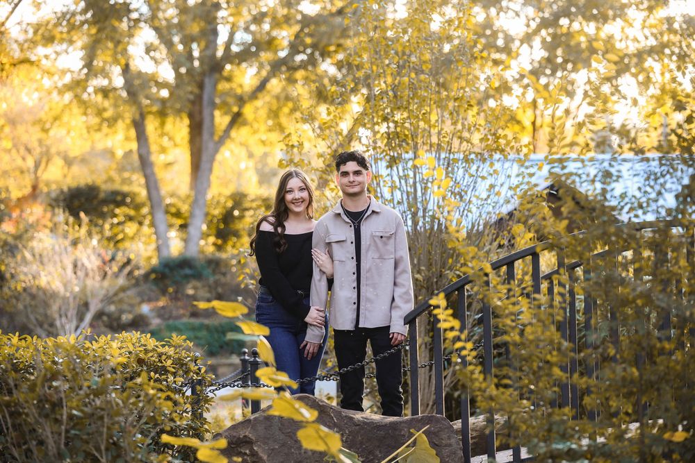 A couple walks together in a park during golden hour autumn sunset with trees glowing in warm light.