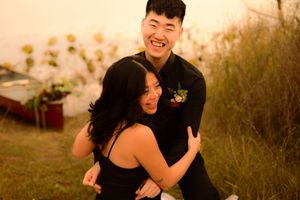 A couple laughs and embraces while dancing together outdoors during golden hour sunset.