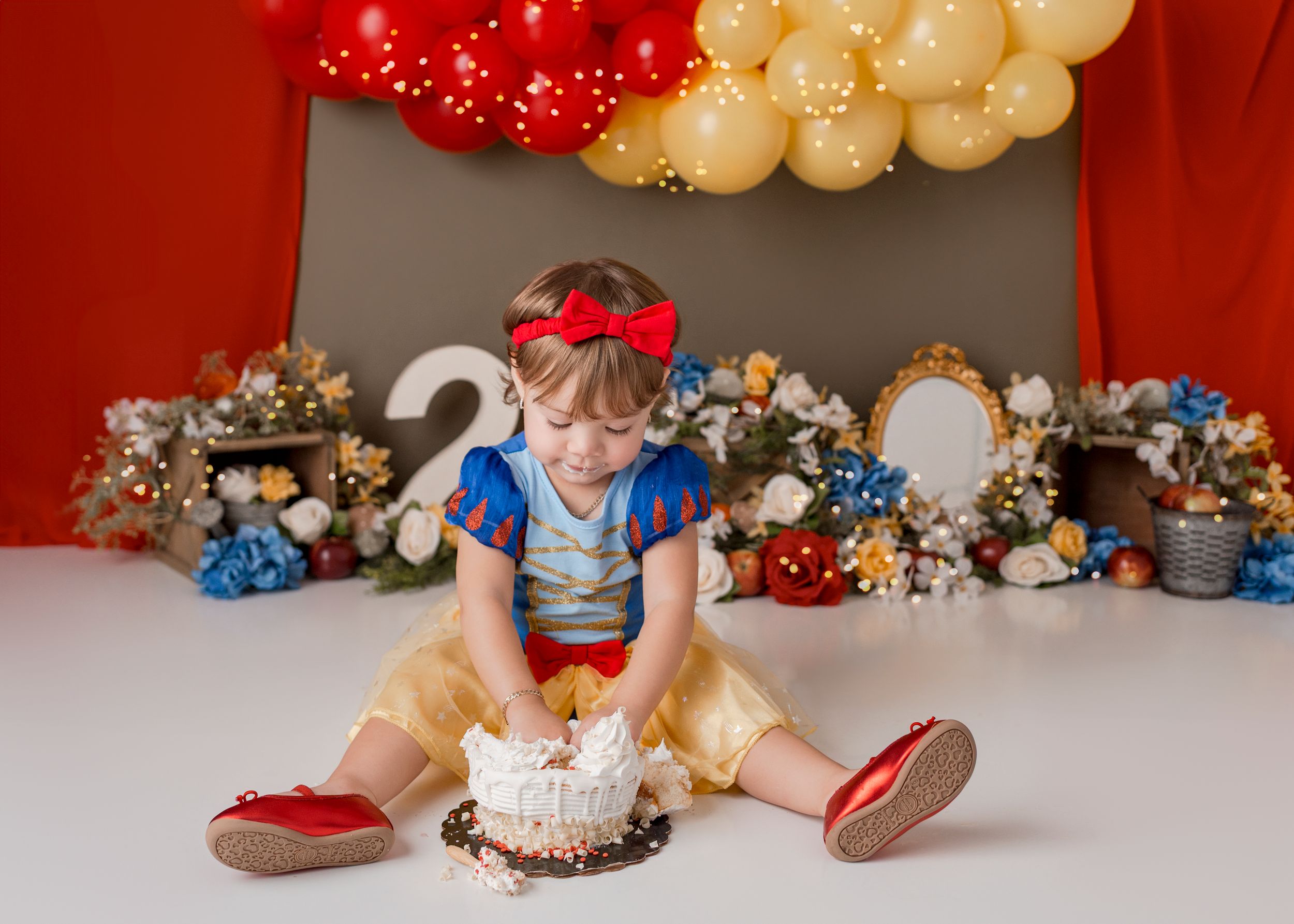 A festive balloon arch in red and gold colors with Christmas ornaments and decorative elements.