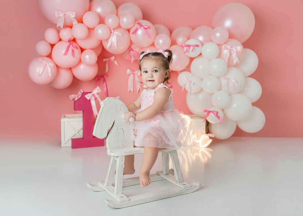 Pink and white balloon decorations create a dreamy backdrop for a first birthday celebration with party decor.