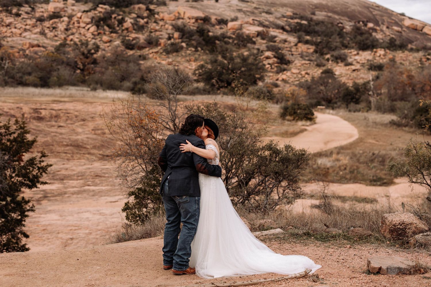 Bride and groom embracing in desert landscape
