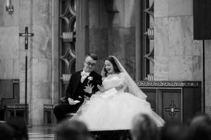 Black and white photo of a joyful couple seated together during their traditional church wedding ceremony.