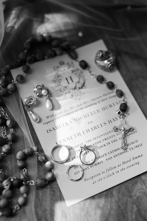Black and white images of wedding invitation text and decoration items arranged artistically on a dark surface.