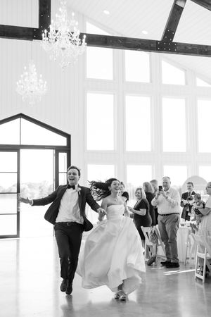 Wedding couple and guests engage in spirited dance moves during reception celebration in bright, modern venue.