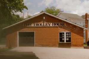 Exterior of The Trolley House, a historic brick wedding venue with large garage door and classic signage.
