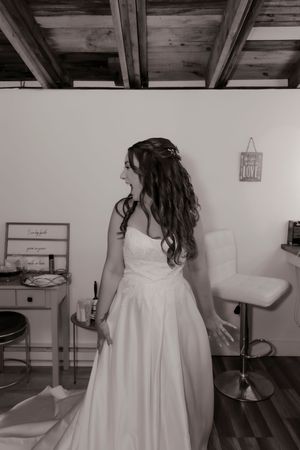 Black and white portrait of bride in strapless wedding gown laughing joyfully in bridal suite.