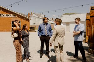 Wedding guests in formal attire socializing outdoors at rustic venue.