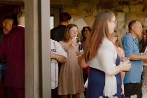 Wedding guests mingle and enjoy drinks during cocktail hour at rustic stone venue.