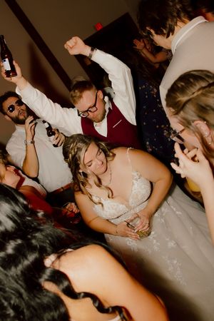Bride in lace gown dancing joyfully with guests at her wedding reception.