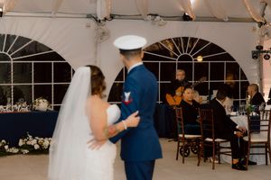 Bride and groom share first dance as guitarist performs at elegant tented wedding reception.