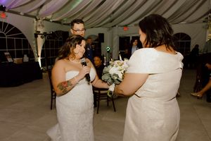 Bride shares bouquet moment with guest at elegant wedding reception.