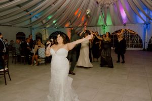 Bride tosses bouquet to excited guests at wedding reception.