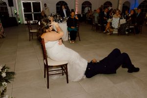 Groom playfully lies on floor during lively wedding reception dance.