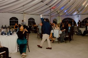 Wedding guests dancing and celebrating at elegant tented reception venue.