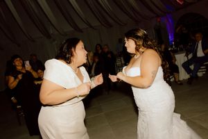 Two brides sharing a joyful dance together at their wedding reception celebration.