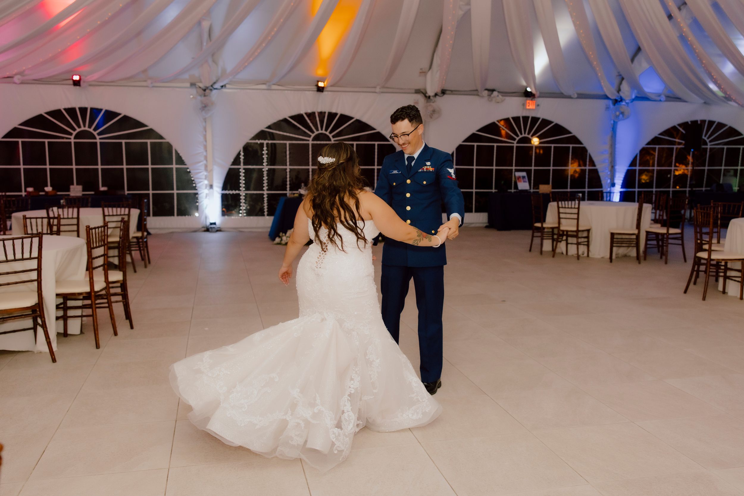 Bride and groom sharing their first dance in a beautifully lit tented wedding venue.
