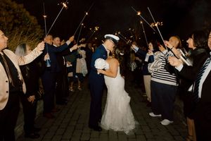 Newlywed couple kissing under sparklers during a romantic wedding sendoff at night.