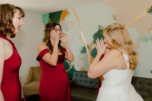 Emotional bridesmaids and bride sharing a joyful first look reaction moment together.