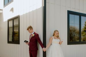 Bride and groom share a first look moment outside a white barn wedding venue.