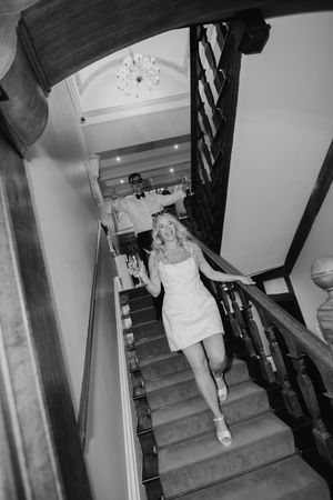 A sequence of black and white photos showing someone in white clothing descending a carpeted staircase with a dark railing.