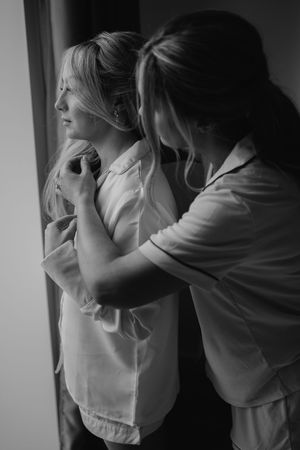 A sequence of black and white photos showing the progression of an emotional embrace between two people in hooded tops.