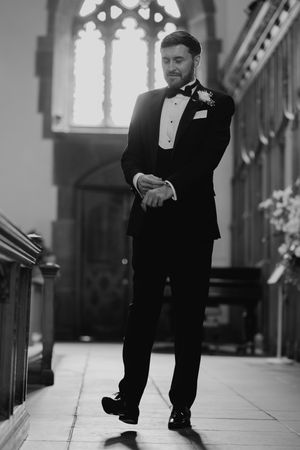 A black and white photo series showing a person in formal attire moving playfully down an elegant hallway.