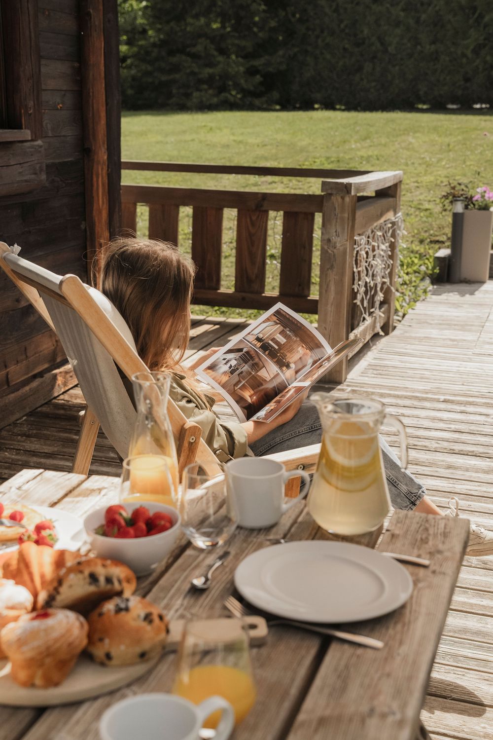 Outdoor terrace dining at a luxury alpine property — guests at a table with drinks on a sunny green lawn — Paul Brechu Photography