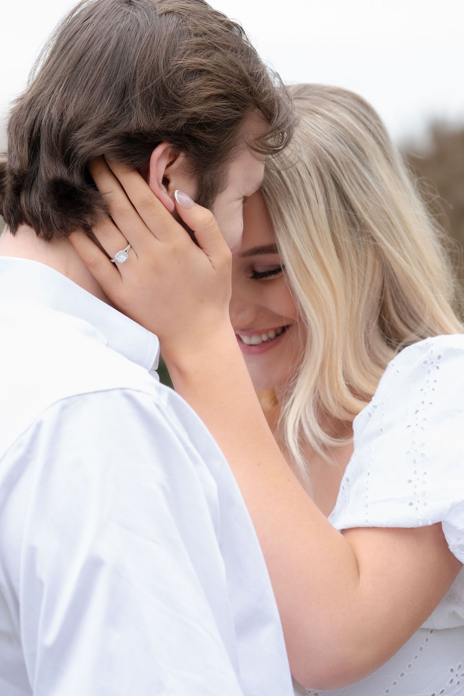 A romantic couple shares an intimate moment during a sunset photoshoot in a grassy field.