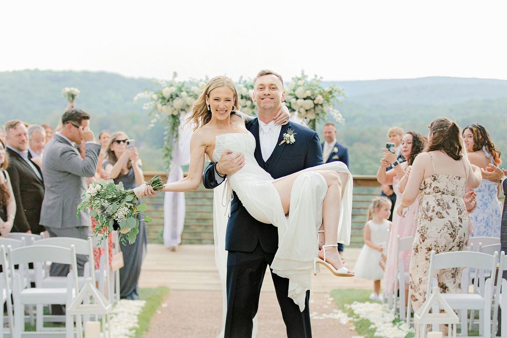 Bride and groom smiling as he carries her down the aisle after their Lewallen Farms wedding ceremony in Georgia.