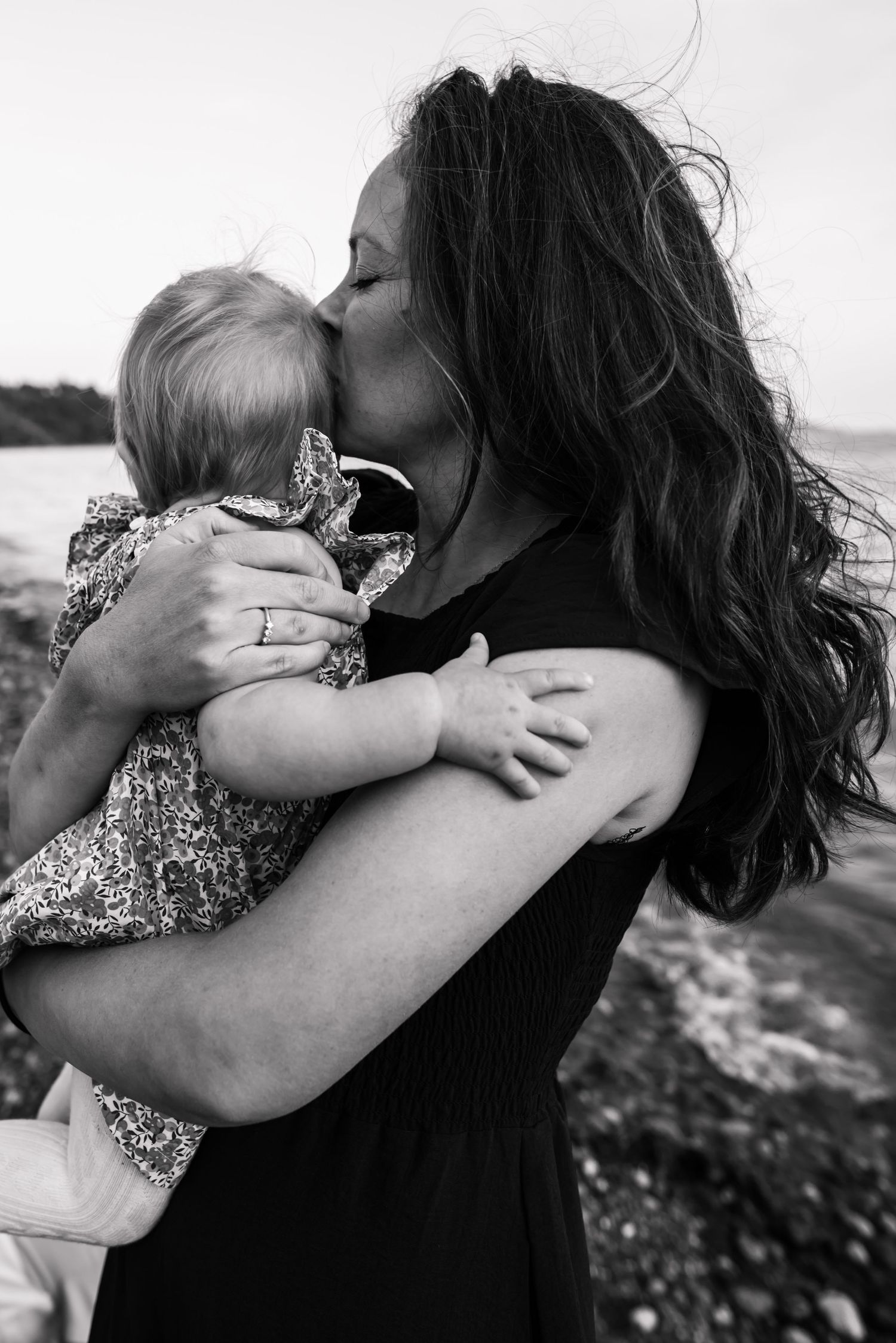 Black and white portrait of an intimate embrace against an ocean backdrop.