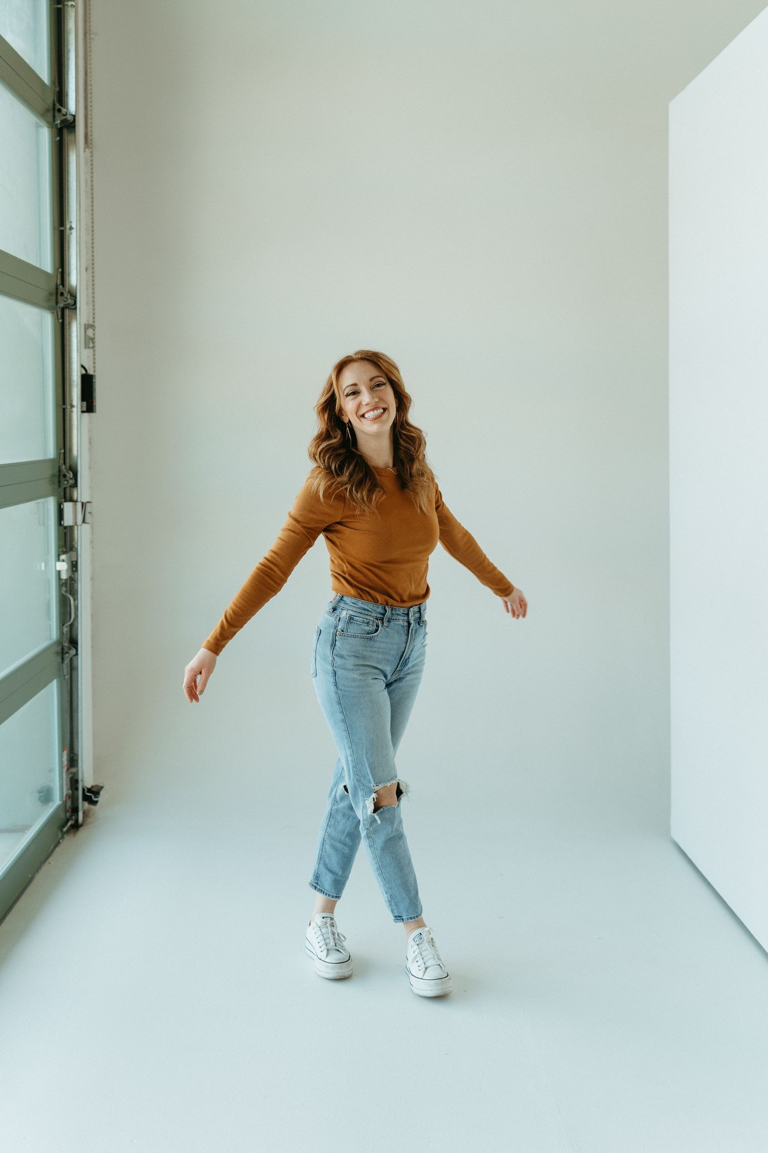 Woman stands in a white studio setting smiling