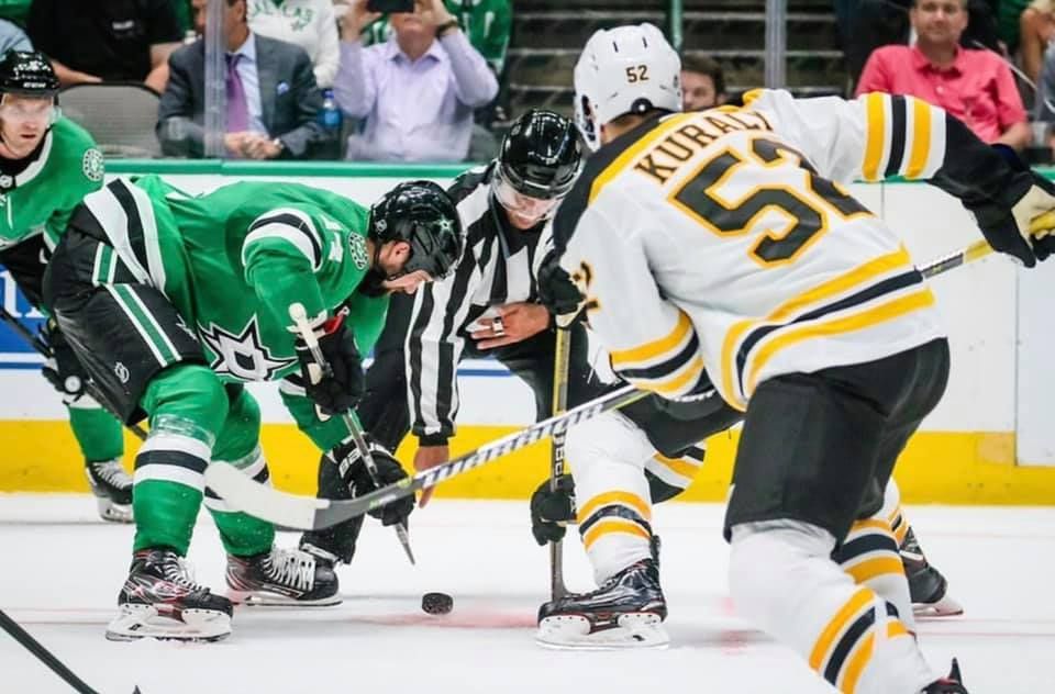 Hockey players from opposing teams battle for control of the puck during an intense NHL game.