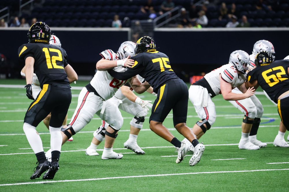 Football players line up at the line of scrimmage during a game on an indoor field.