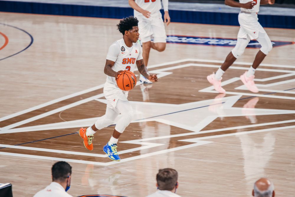 Basketball players in action on court during competitive game.