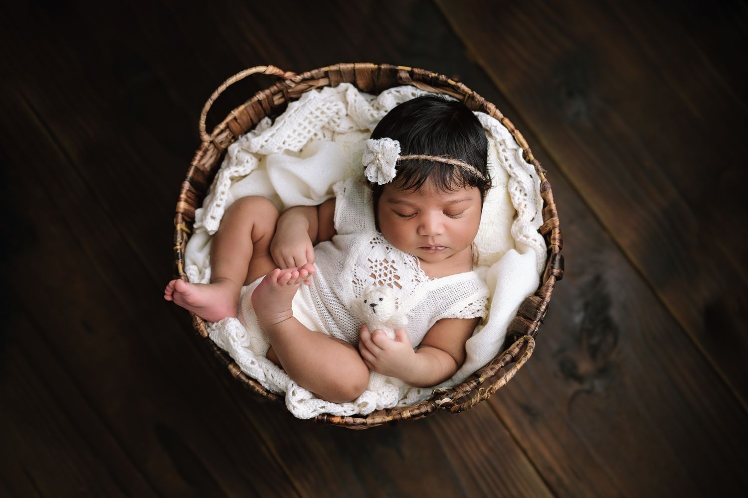 Newborn studio session with a baby girl posed in a vintage-style basket